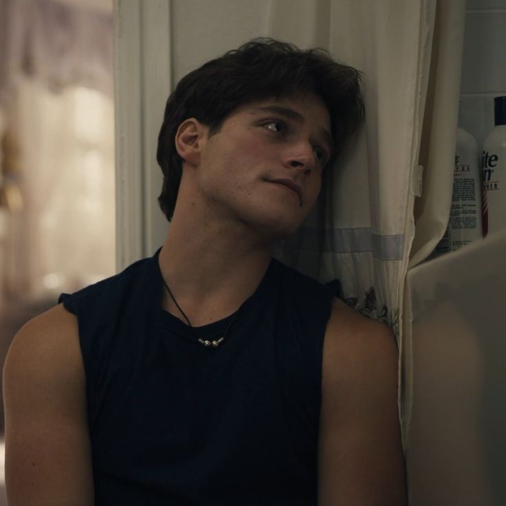 a young man is leaning against the wall