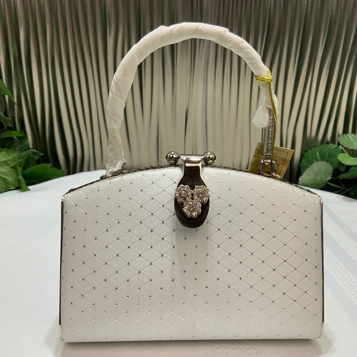 Beautiful Little Evening Purse. White Satin With Little Metal Dots In Shape Of 3 Dimensional Square, Lock Ornate With Crystals And The Metal Handle Carved. Inside Is One Pocket With Zipper. 5 Inches Tall, 6 1/2 Inches Wide. Very Elegant Little Purse. White Satchel Shoulder Bag For Party, White Party Satchel Bag, White Satchel Evening Bag For Party, White Satchel Evening Bag, White Clutch Bag For Formal Occasions, Elegant White Shoulder Bag Clutch, White Clutch With Detachable Handle, White Clutch With Detachable Handle As Shoulder Bag, Luxury White Shoulder Bag Clutch