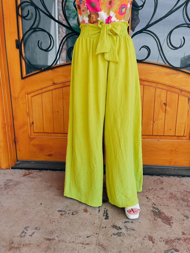 Elevate your style with our "She Stands Out" pants. These high-waisted palazzo pants offer both comfort and airflow, perfect for any occasion. The self-tie in the front and smocked back add a touch of elegance to these vibrant lime-colored pants. Feel confident and stand out in the crowd with our statement piece. Paired with our 'Petal Picking' Top and our 'Work of Art' Top Inseam: 30" Model is 5'1 and has on 3" block heels Wide Leg Pants For Summer Vacation, Trendy Wide Leg Pants For Vacation, Summer High-waisted Wide Leg Pants In Solid Color, Summer High-waisted Wide Leg Pants Solid Color, Chic Summer Wide Leg Pants In Solid Color, Chic Summer Wide Leg Pants Solid Color, Spring Wide Leg Ankle-length Pants With Tie Waist, Chic Wide Leg Pants For Summer, Spring Ankle-length Wide Leg Pants With Tie Waist