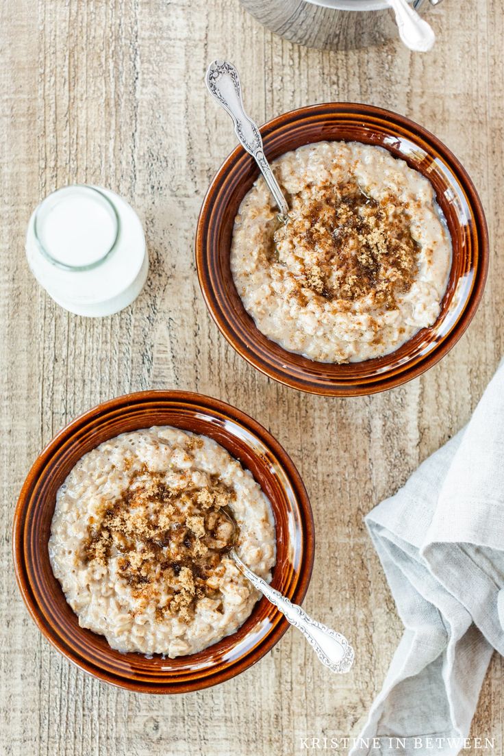 two brown bowls filled with oatmeal next to a cup of milk