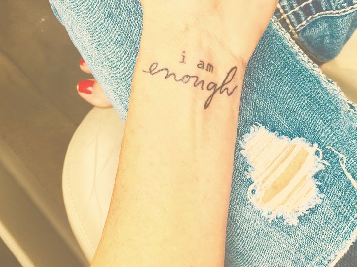 a woman with a tattoo on her arm saying i am enough