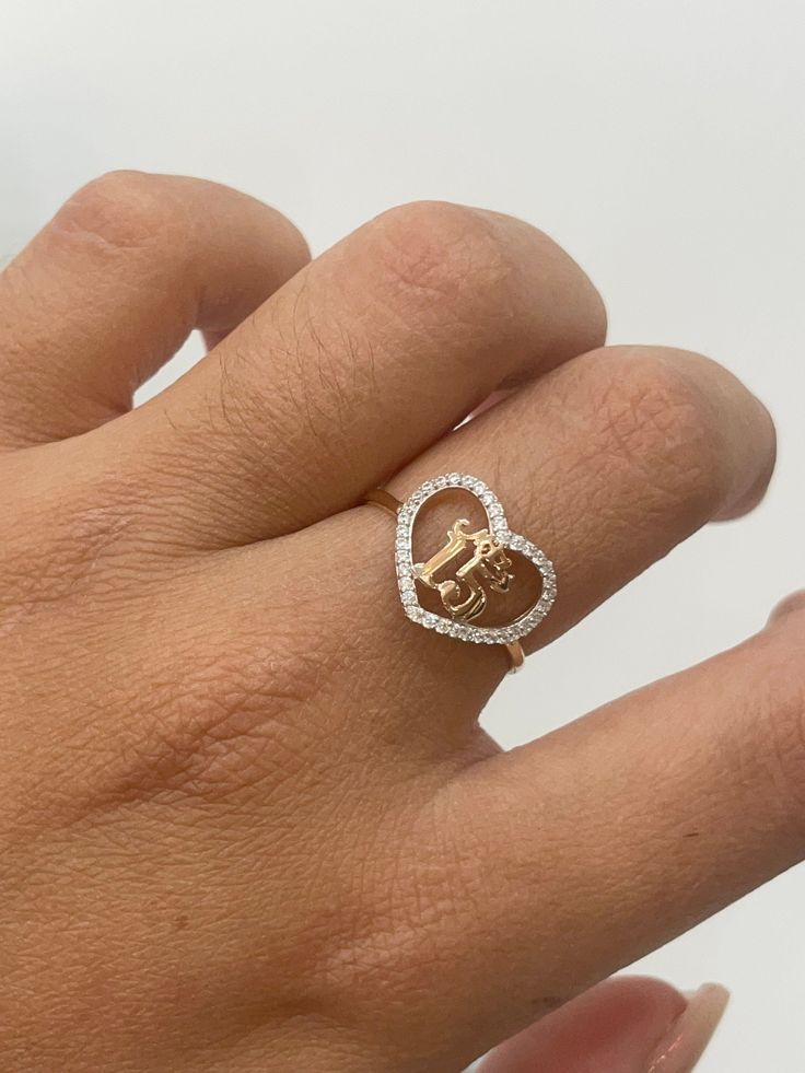 a woman's hand with a gold and diamond heart shaped ring on her finger