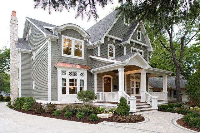 a large gray house with white trim on the front porch and stairs leading up to it