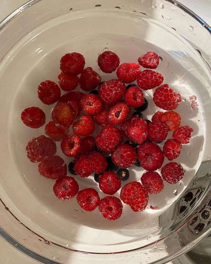 raspberries in a bowl with water on the side