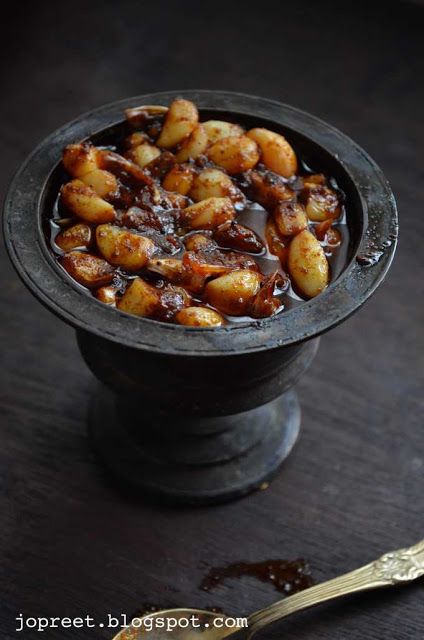 a bowl filled with food sitting on top of a wooden table next to a spoon