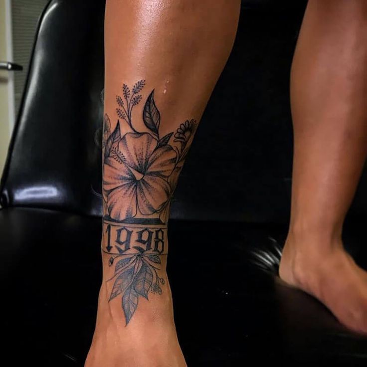 a woman's foot with flowers and the word love tattooed on her left leg