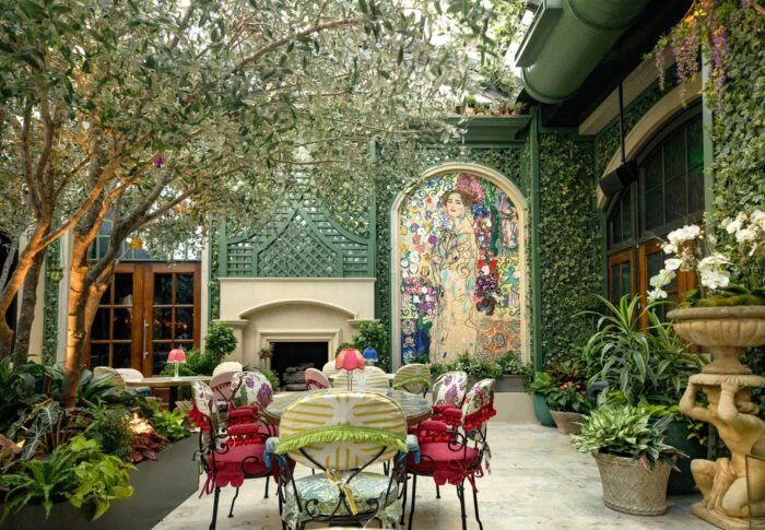 an outdoor dining area with tables, chairs and potted plants on either side of the patio