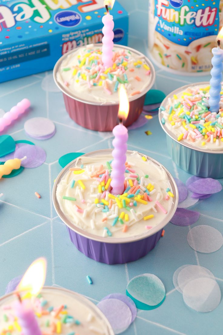 birthday cupcakes with candles and sprinkles on a blue tablecloth