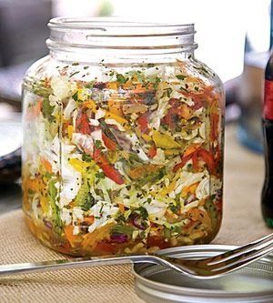 a jar filled with food sitting on top of a table next to a bottle of beer