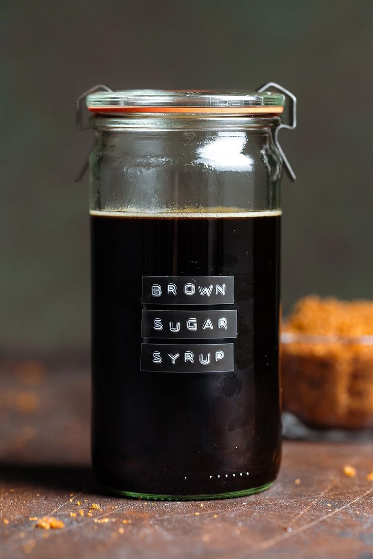 a glass jar filled with liquid sitting on top of a wooden table next to a piece of bread