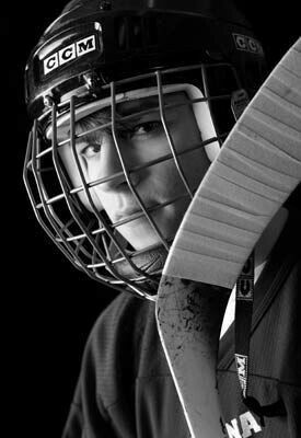 a black and white photo of a young man wearing a hockey goalie's helmet