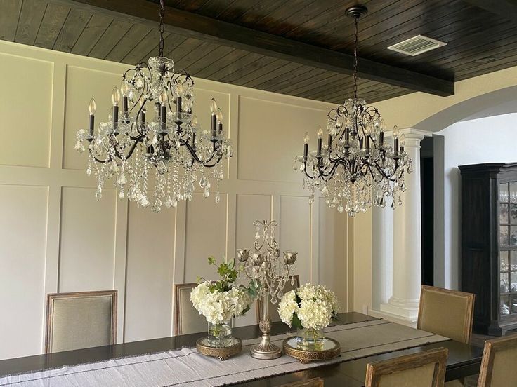 an elegant dining room with chandeliers and flowers in vases on the table