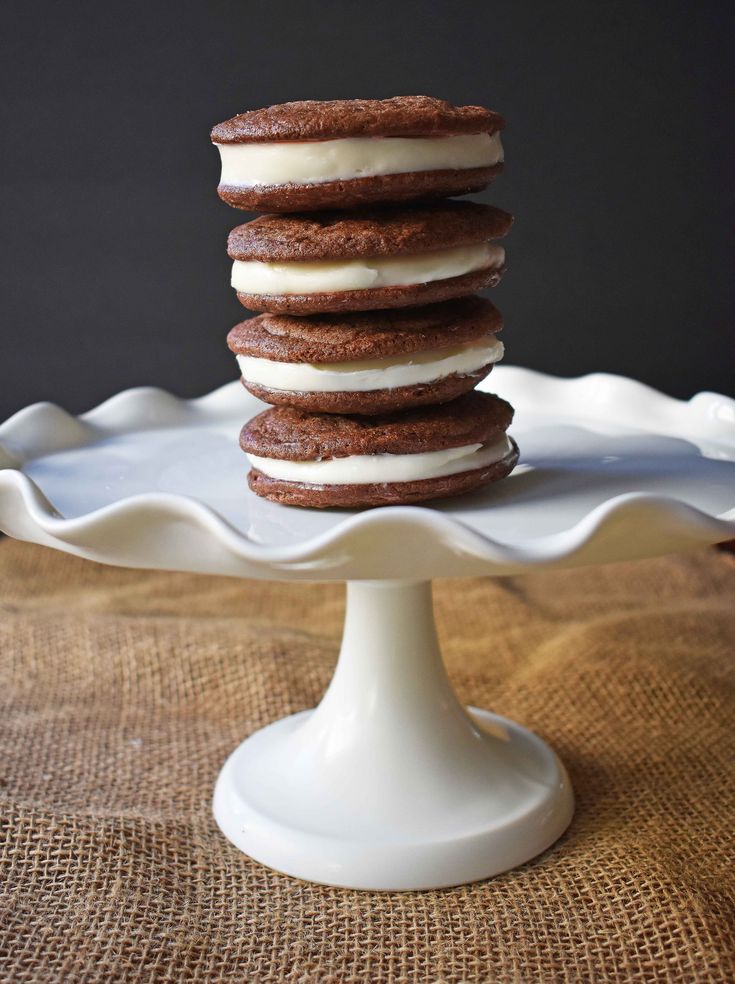 a stack of cookies sitting on top of a white cake platter with frosting