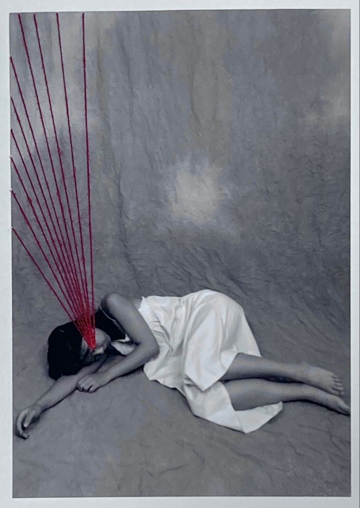 a woman laying on the ground with red strings coming out of her head and arms