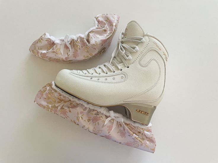 a pair of white roller skates with pink and gold lace on the soles