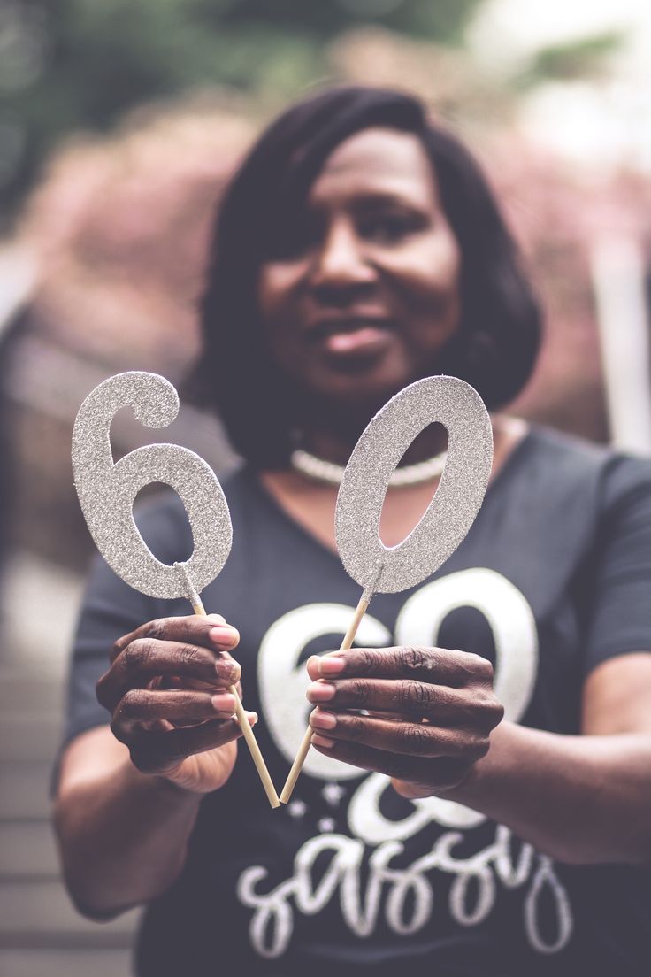 a woman is holding two cake picks with the number 60 on them in front of her