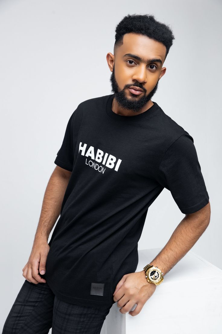 Introducing the Men's Black Short Sleeve Habibi London Classic Logo T-shirt. A bold and sophisticated piece, this tee features a striking Habibi London logo on the chest and a genuine leather-look badge for a touch of luxury. Crafted from 100% organic cotton, it's both comfortable and stylish, exuding an air of mystery and confidence. Key features: Habibi London logo on the chest Genuine leather-look badge Made from 100% organic cotton Comfortable and breathable Versatile styling options London Logo, Black Shorts Men, Classic Logo, Bold Fashion, Logo T Shirt, Black Shorts, Tshirt Logo, Genuine Leather, Organic Cotton