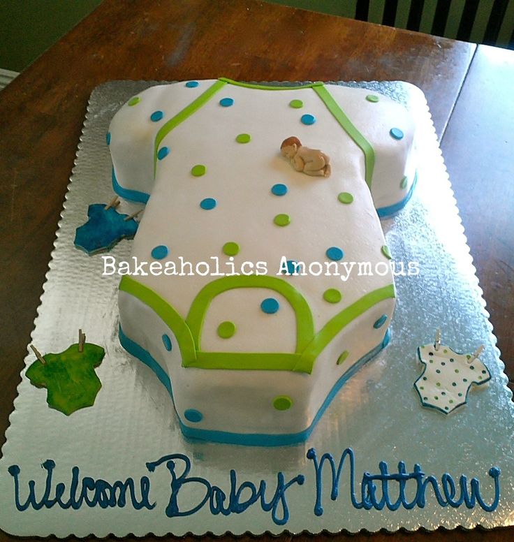 a baby shower cake on a table with blue and green decorations, including a teddy bear