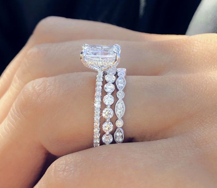 a woman's hand holding an engagement ring with diamonds on the band and side stones