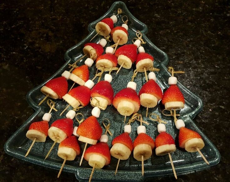 a christmas tree shaped tray filled with fruit and marshmallows on skewers