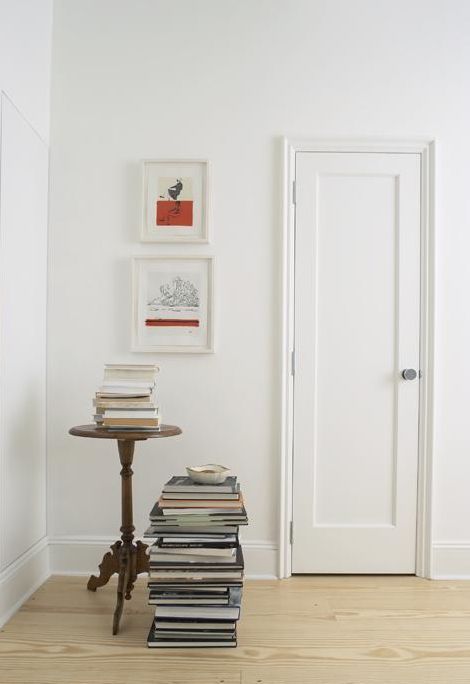 a stack of books sitting on top of a wooden table next to a white door