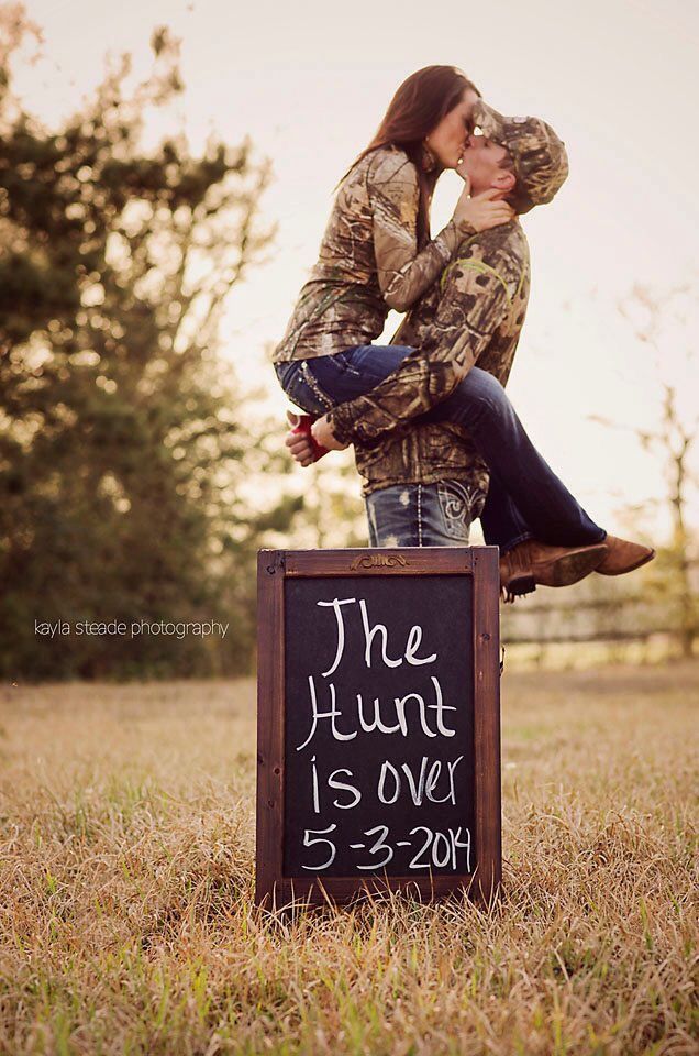 a man and woman sitting on top of a sign that says the hunt is over