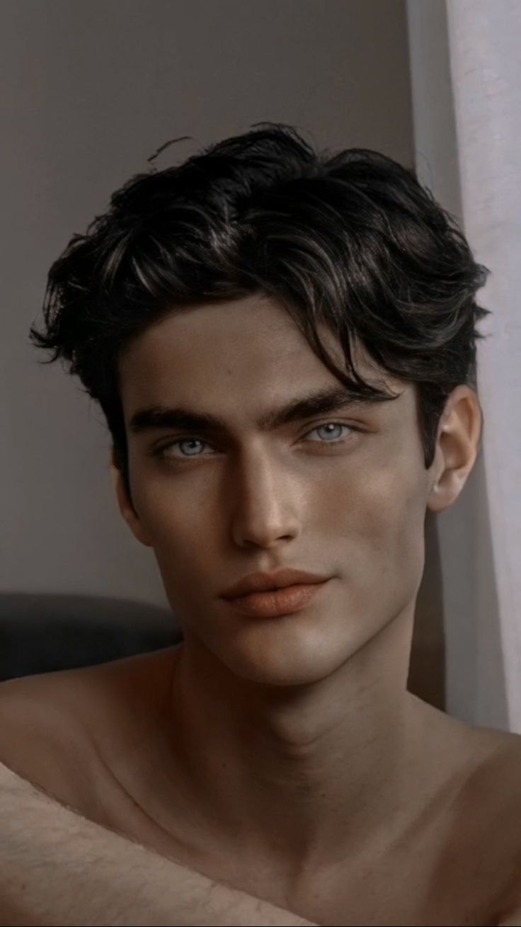 a close up of a person with blue eyes and a shirtless man in the background