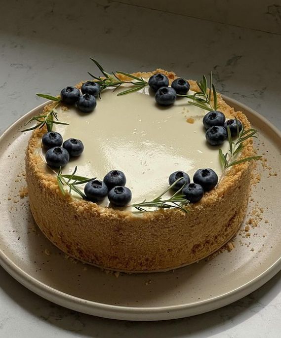 a cheesecake with blueberries and rosemary on top