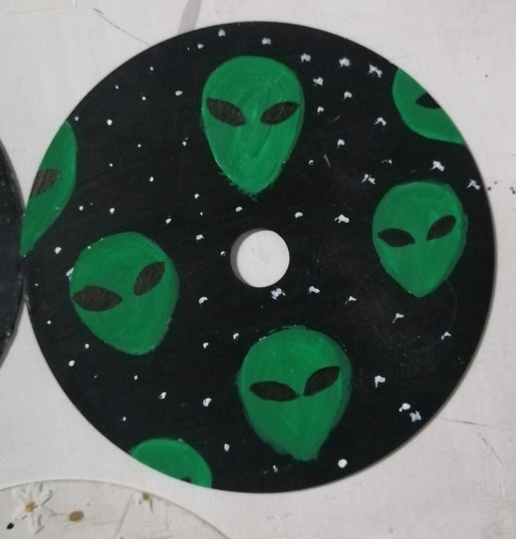 two black and green plates with alien faces on them, one is painted to look like an alien