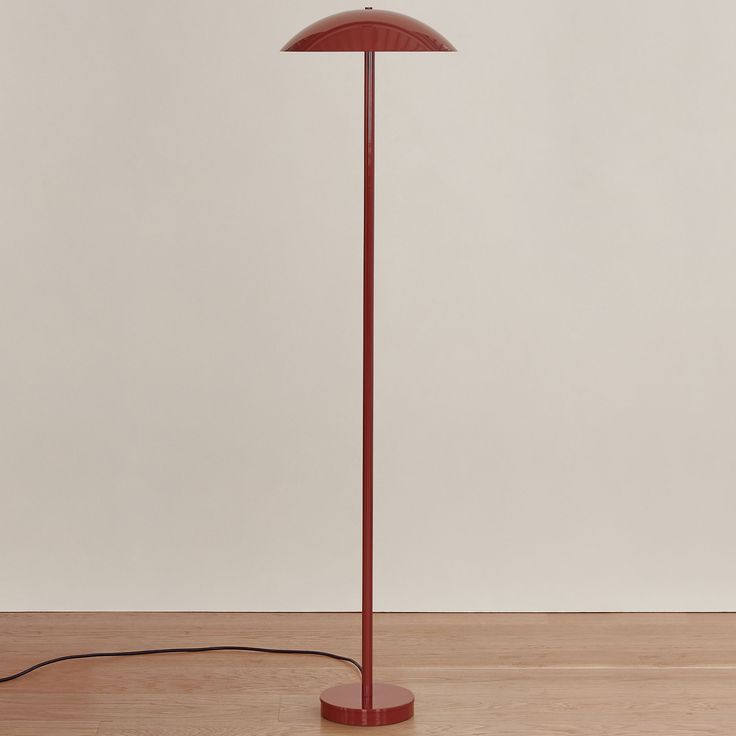 a red floor lamp sitting on top of a wooden table