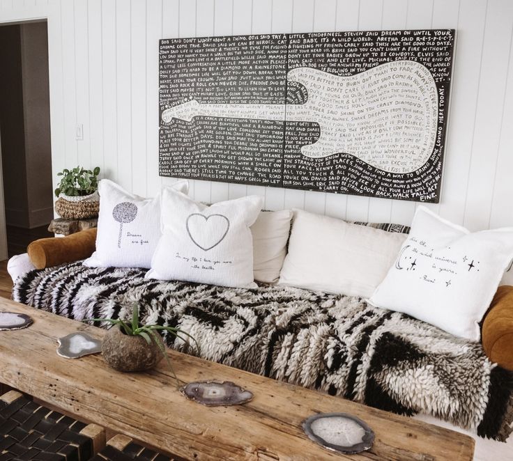 a couch with several pillows on it in front of a guitar wall hanging above the couch