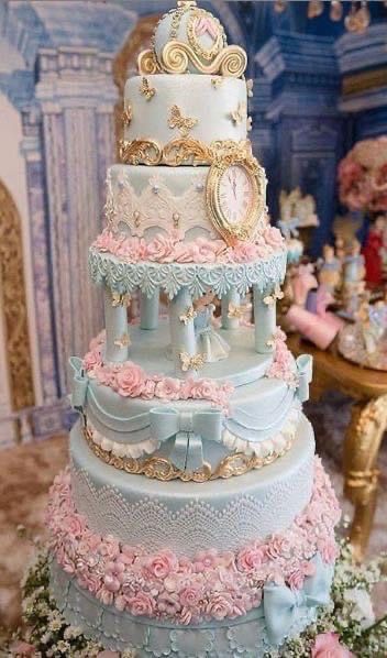 a multi layer cake with pink and blue flowers on the bottom tier, topped with a clock