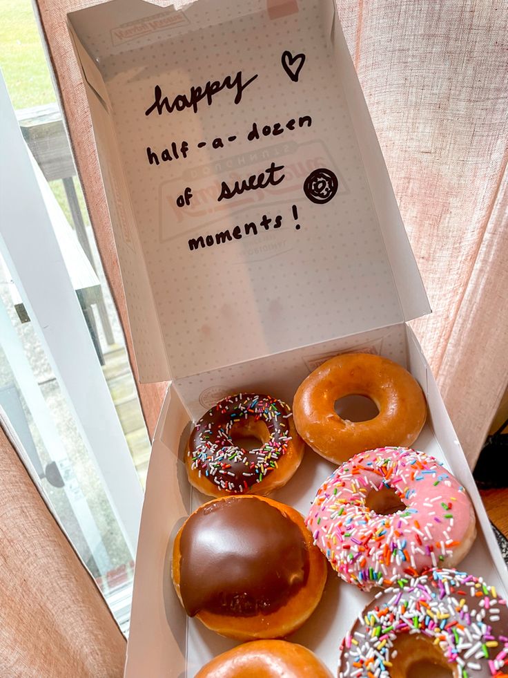 a box filled with lots of doughnuts on top of a window sill