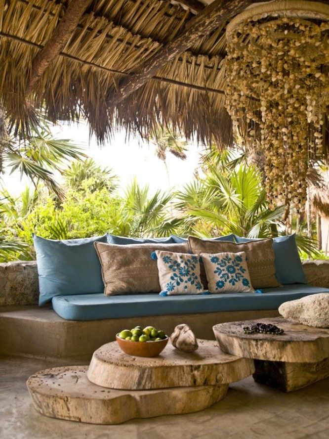 an outdoor seating area with blue cushions and pillows on top of wooden benches, surrounded by palm trees