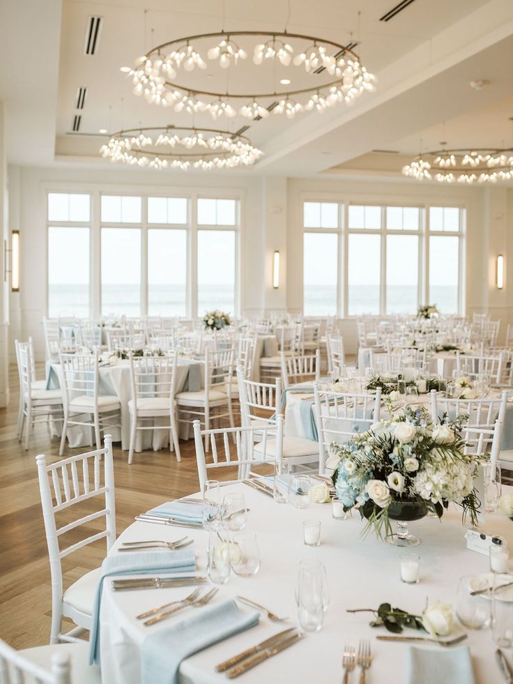 the tables are set with white and blue linens for an elegant wedding reception at the beach