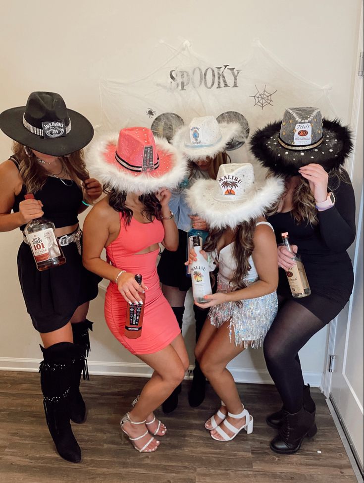 three women dressed up in costumes and hats posing for the camera with bottles of booze