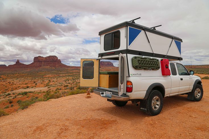 a white truck with a camper attached to the back parked on a dirt road