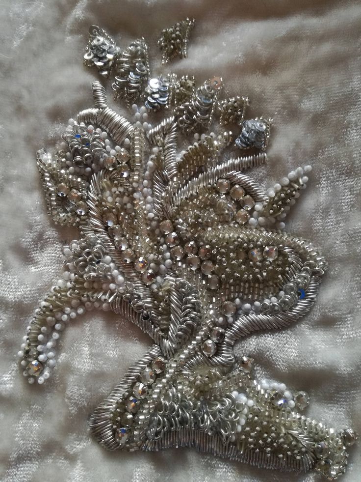 Handmade silver cannetlle, shiny stones, sequins and pearls embroidered flower. Unique piece made entirely by hand with great precision work. The flower is on a beige velvet backing dimensions: height height: 13 cm wide width: 7.5 cm Elegant Embellished Embroidered Fabric For Formal Occasions, Elegant Pearl Embroidered Fabric For Celebration, Elegant Embroidered Fabric For Celebration, Elegant Hand Embellished Embroidered Fabric For Wedding, Elegant Embellished Embroidered Fabric For Festive Season, Elegant Embroidered Fabric With Pearl Embroidery For Reception, Elegant Embroidered Fabric With Sequins For Formal Use, Elegant Embroidered Fabric With Sequins For Formal Occasions, Elegant Formal Embroidered Fabric With Sequins