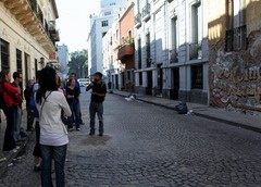 people are standing on the street in front of some buildings and one person is holding a cell phone