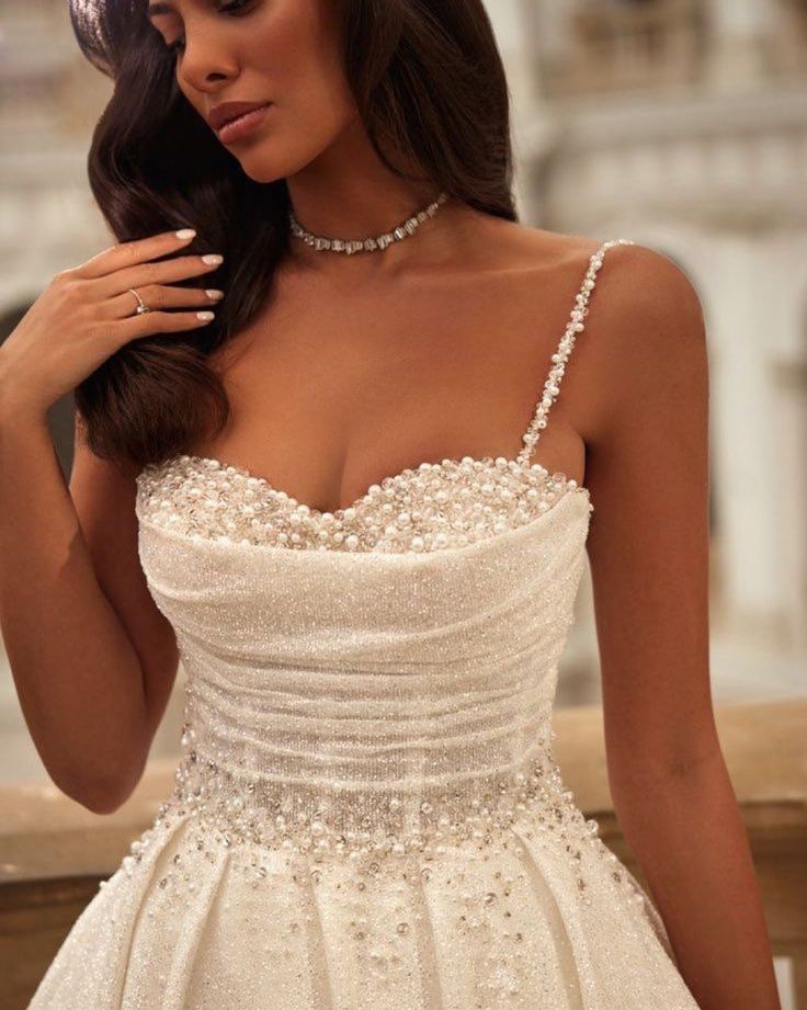 a woman in a wedding dress posing with her hand on her shoulder and wearing a tiara