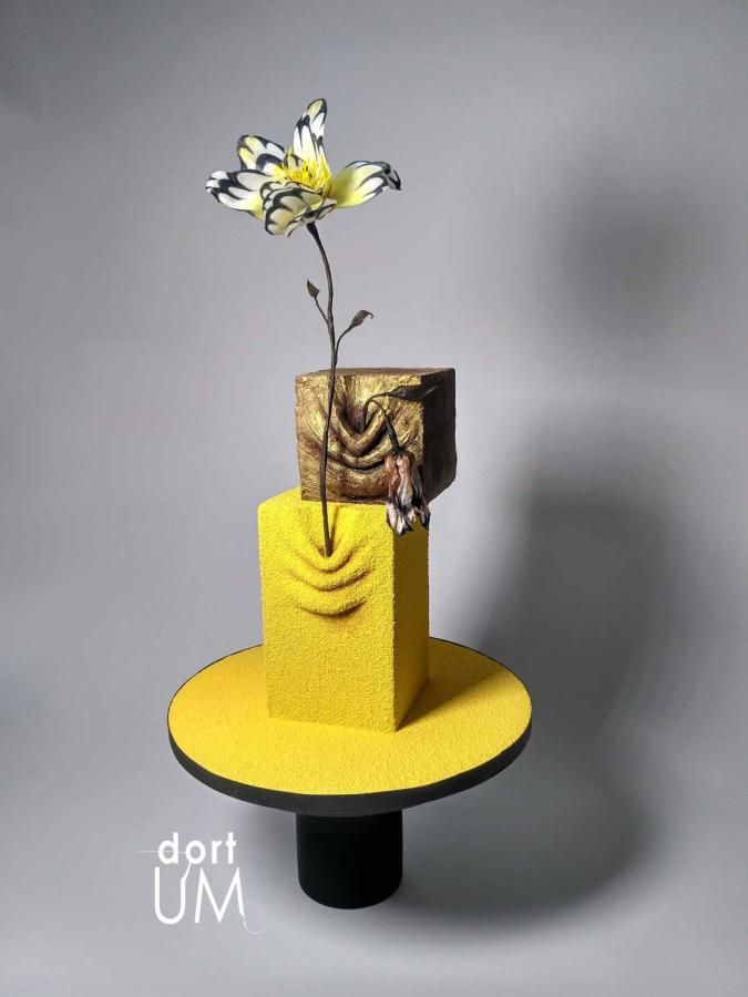 a yellow and black stand with a flower in it