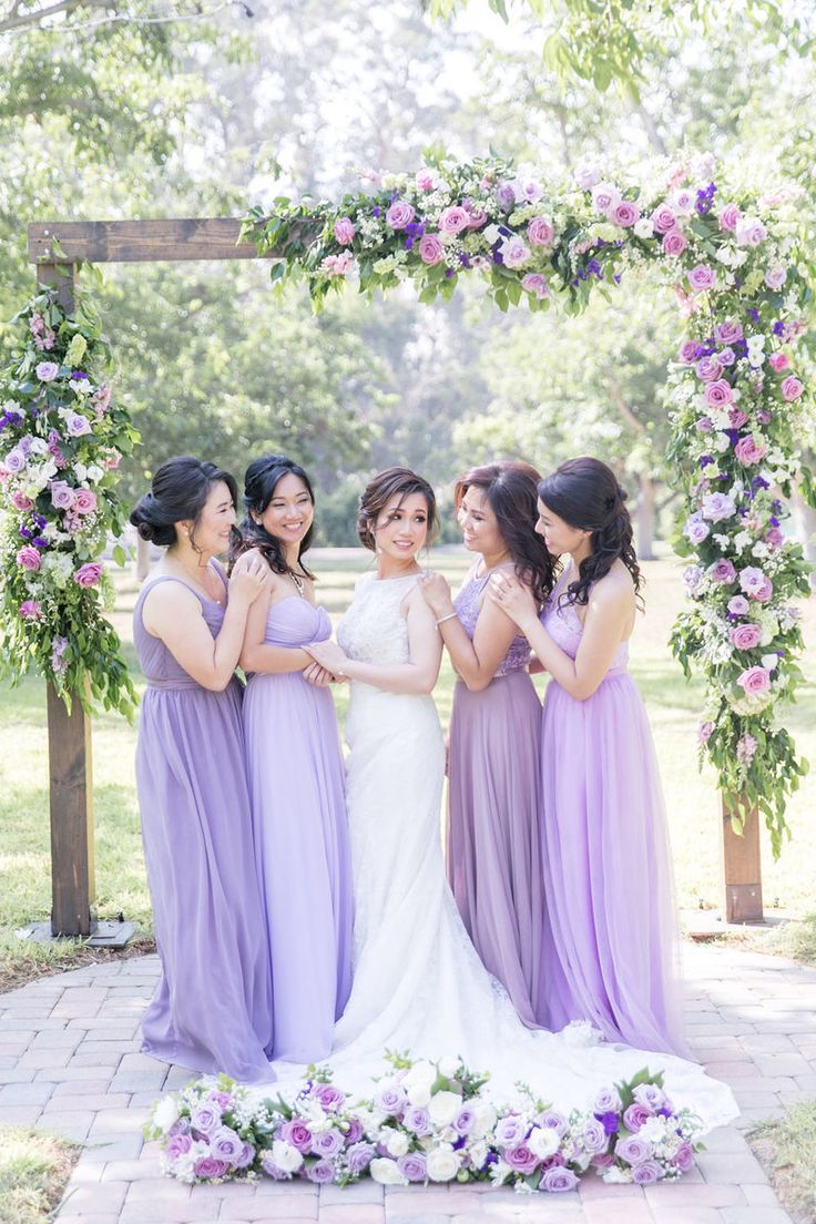 the bride and her bridesmaids pose for a photo in front of an arch decorated with flowers