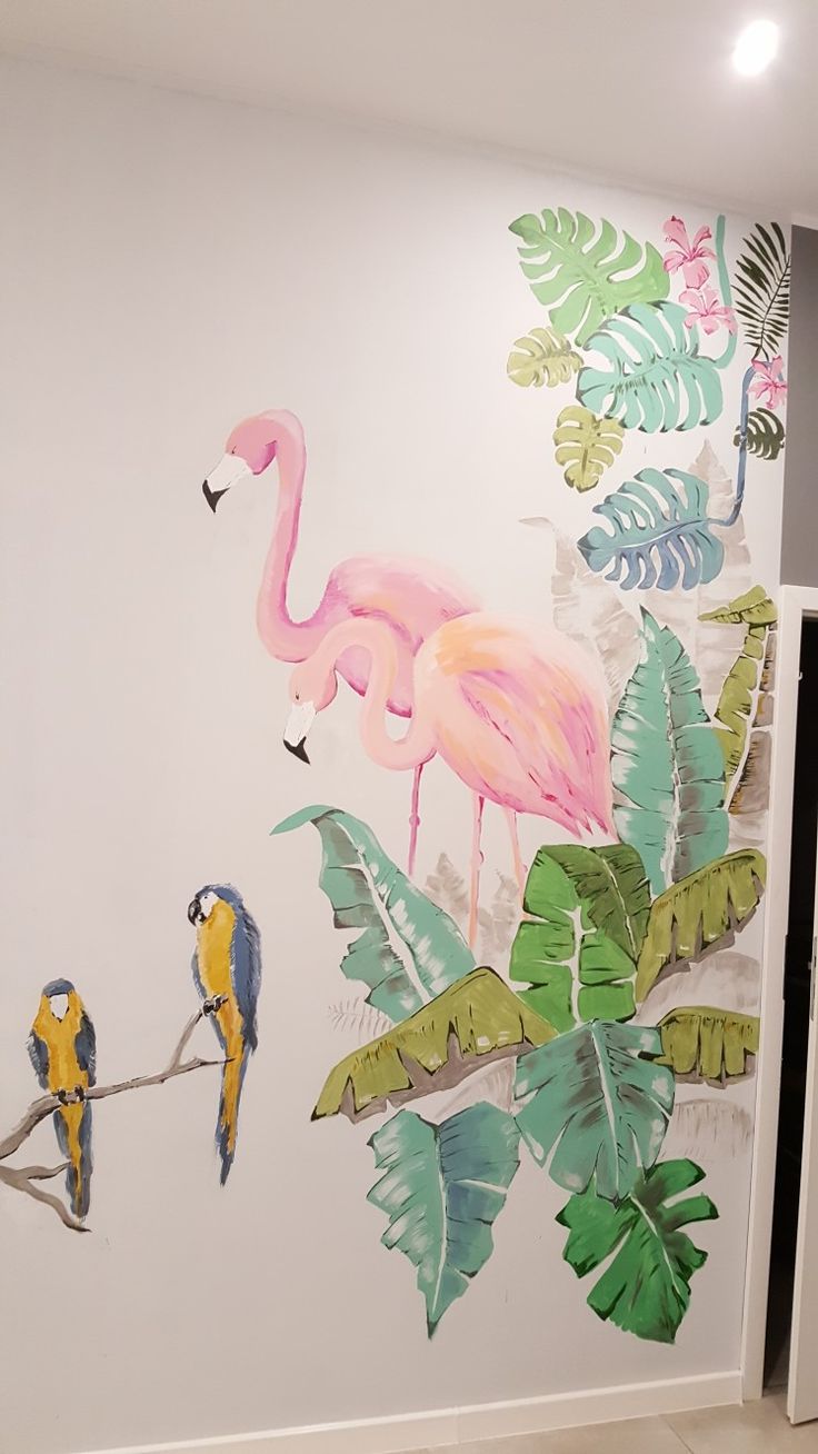 the wall is painted with tropical leaves and flamingos on it, while two birds are perched on a branch