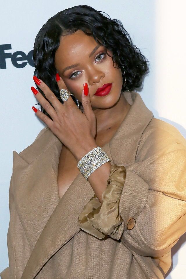 a close up of a person with her hand on her face and wearing red nail polish