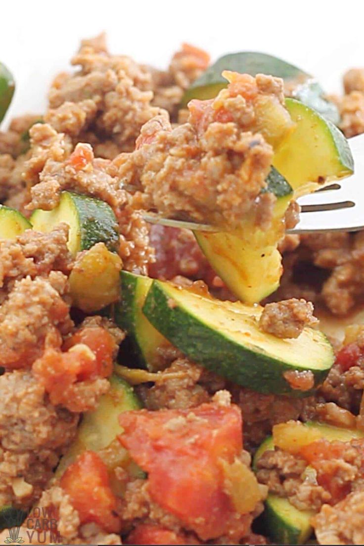 a close up of a fork in a dish with zucchini and meat on it