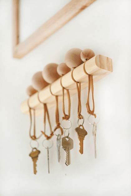 several keys hang on a wooden rack in front of a mirror