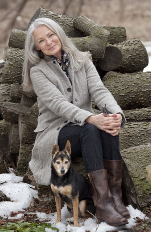 a woman sitting on a bench with her dog in front of snow - covered rocks