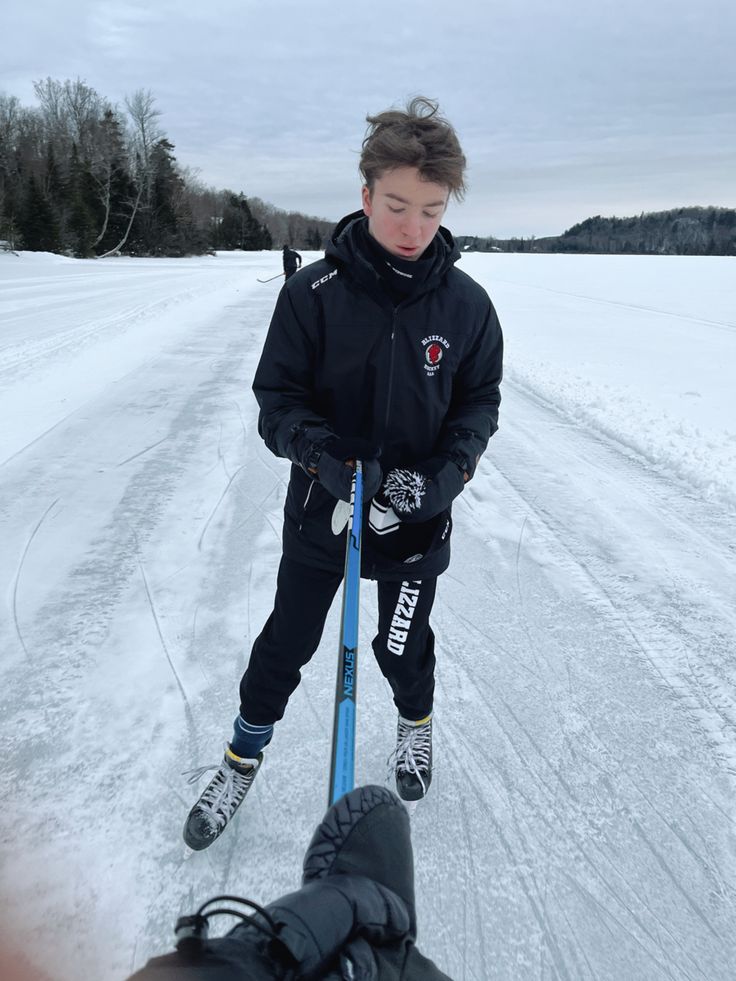 a young boy riding skis on top of snow covered ground next to a person