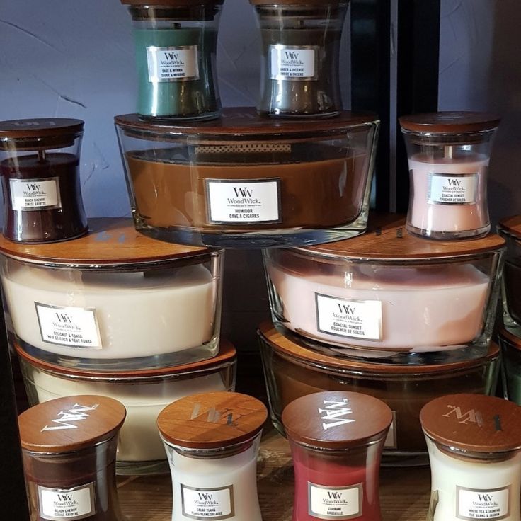 many different types of candles on display in glass containers with labels for each candle type