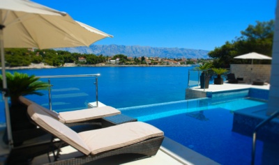 an empty swimming pool with lounge chairs and umbrellas next to it, overlooking the water